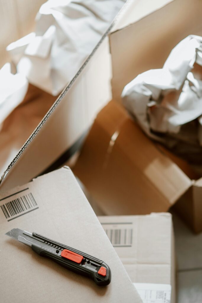 pexels-photo-4792548-4792548 From above of utility knife on heap of carton boxes with crumpled papers during relocation