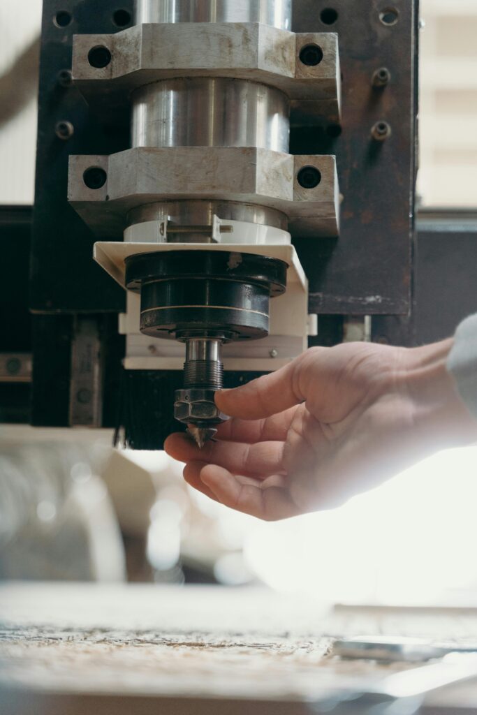 pexels-photo-7480233-7480233 Detailed shot of a CNC machine spindle being adjusted by a human hand in a workshop setting.